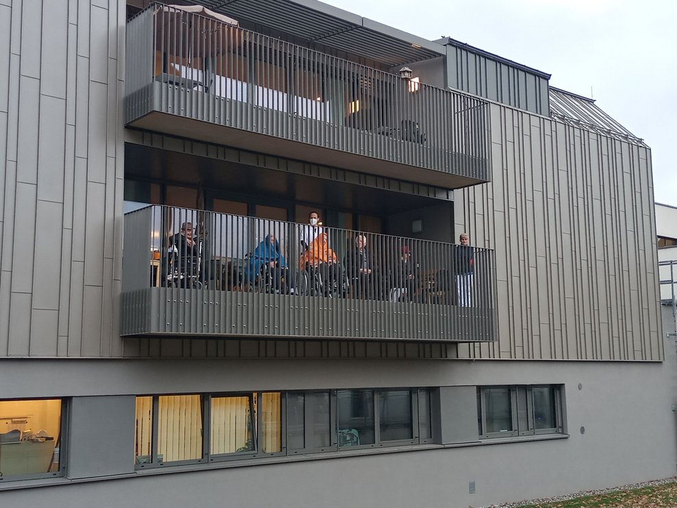 BewohnerInnen stehen am Balkon. 
