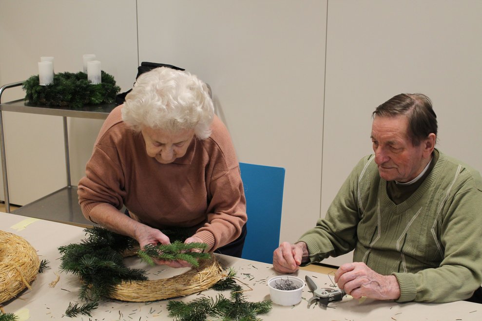 Zwei Personen beim Adventkranzbinden.